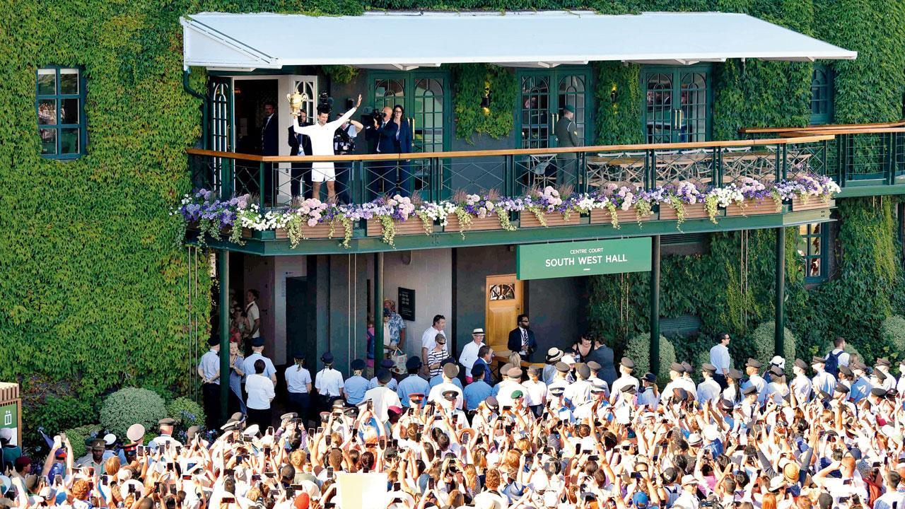 રવિવારે સાતમી વાર વિમ્બલ્ડનની ટ્રોફી જીત્યા પછી સેન્ટર કોર્ટના સ્ટેડિયમની બાલ્કનીમાંથી ચાહકોનું અભિવાદન ઝીલી રહેલો નોવાક જૉકોવિચ. (તસવીર : એ.પી.)