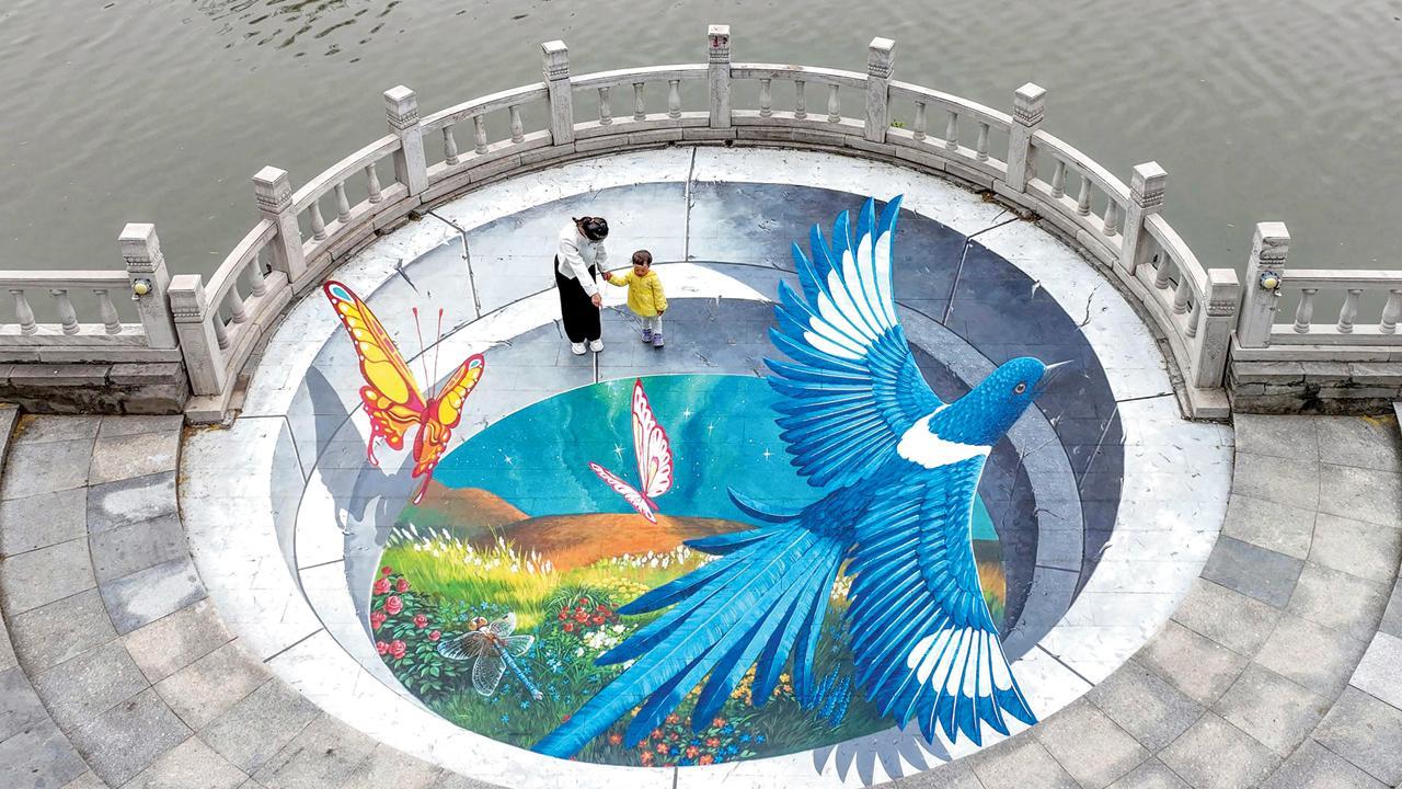 ચીનના ઉત્તરમાં આવેલા હેબેઈ પ્રૉવિન્સમાં હૅન્દનમાં રસ્તા પર તૈયાર કરવામાં આવેલા થ્રી-ડી સ્ટ્રીટ પેઇન્ટિંગને માણી રહેલા અને આ પેઇન્ટિંગની સાથે ફોટોગ્રાફ ક્લિક કરાવી રહેલા લોકો. તસવીર એ.એફ.પી.