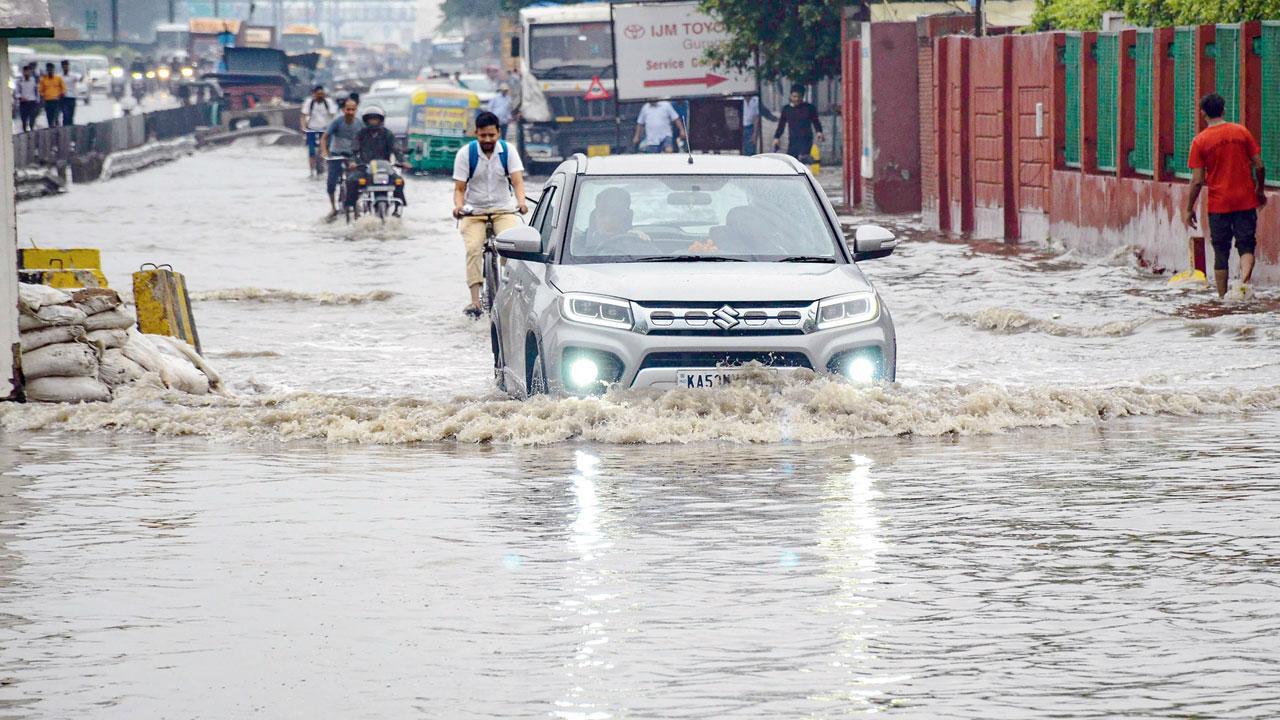 દિલ્હી-ગુરુગ્રામ એક્સપ્રેસવે સર્વિસ રોડ પર ગઈ કાલે ભારે વરસાદ બાદ પાણી ભરાતાં એમાંથી પસાર થઈ રહેલાં વાહનો