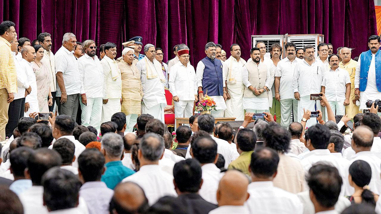 બૅન્ગલોરમાં રાજભવન ખાતે ગઈ કાલે શપથગ્રહણ સમારોહ દરમ્યાન કૅબિનેટમાં નવા સામેલ પ્રધાનોની સાથે કર્ણાટકના રાજ્યપાલ થાવરચંદ ગેહલોટ, મુખ્ય પ્રધાન સિદ્ધારમૈયા અને ડેપ્યુટી સીએમ ડી. કે. શિવકુમાર (તસવીર : પી.ટી.આઇ.)