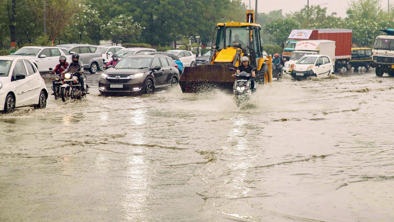 નોએડામાં ગઈ કાલે ભારે વરસાદ બાદ પાણીમાં સમાયેલા રસ્તા પરથી પસાર થઈ રહેલા લોકો. તસવીર પી.ટી.આઇ.