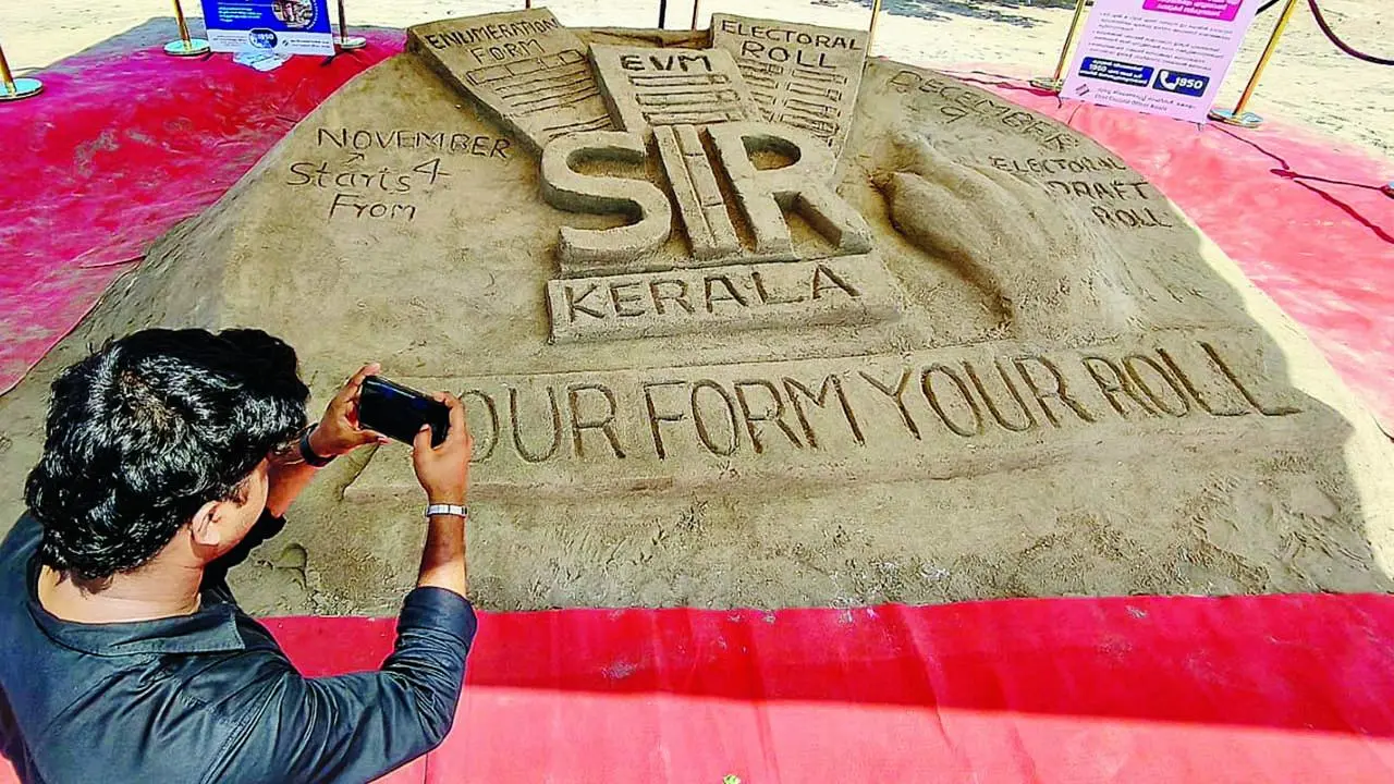 SIR વિશે કેરલાના કોઝિકોડમાં બનાવવામાં આવેલા રેતશિલ્પનો ફોટો પાડતી એક વ્યક્તિ.