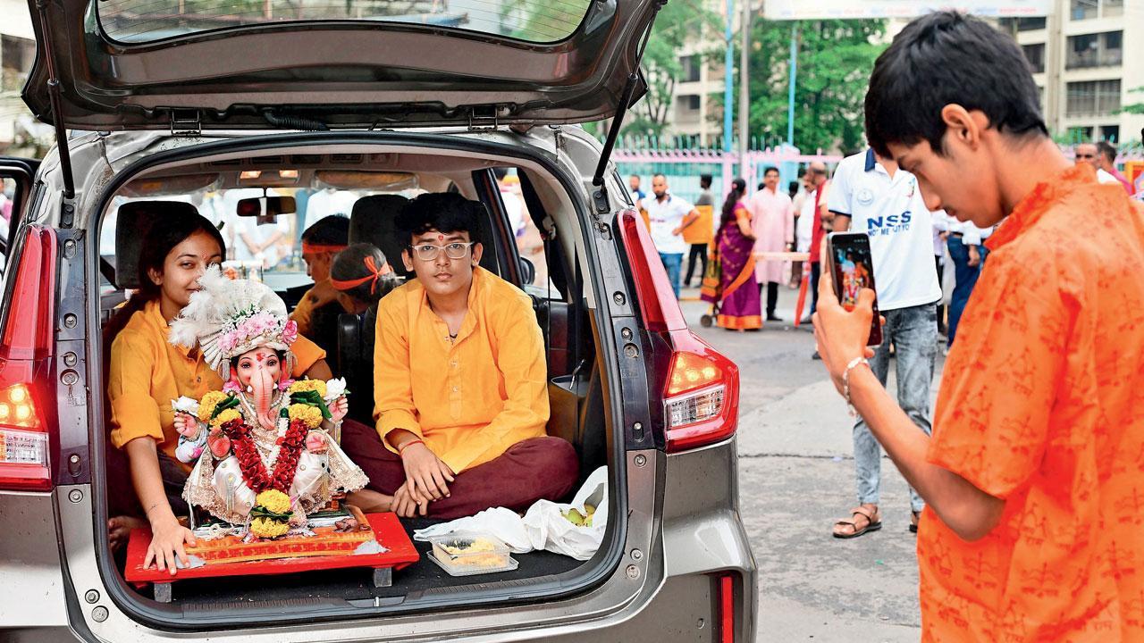 ગઈ કાલે કાંદિવલી વિલેજમાં બનાવવામાં આવેલા કૃત્રિમ તળાવમાં વિસર્જન માટે ગણપતિની મૂર્તિને કારની ડિકીમાં લઈ આવેલા ભક્તો. તસવીર : નિમેશ દવે