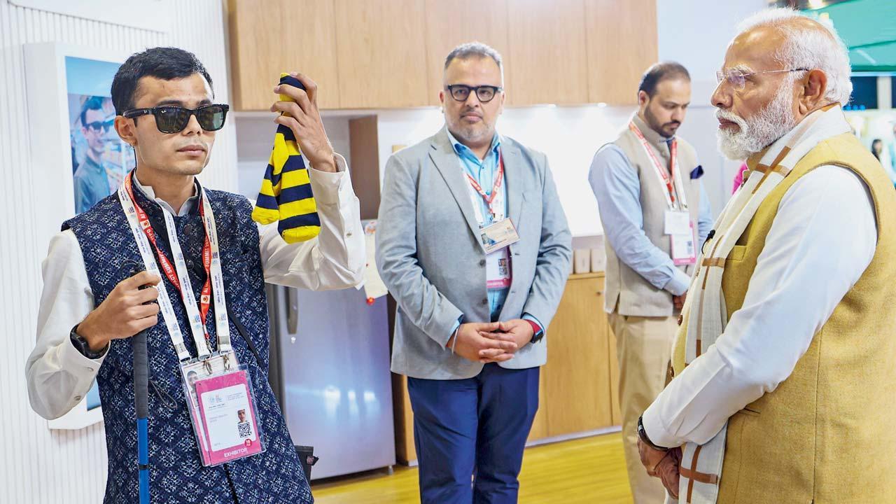 AI ઇમ્પૅક્ટ સમિટ 2026માં પ્રજ્ઞાચક્ષુ માટે તૈયાર કરવામાં આવેલાં AI-સંચાલિત ચશ્માંની માહિતી નરેન્દ્ર મોદીને આપી રહેલો પ્રણવ સાવલા.