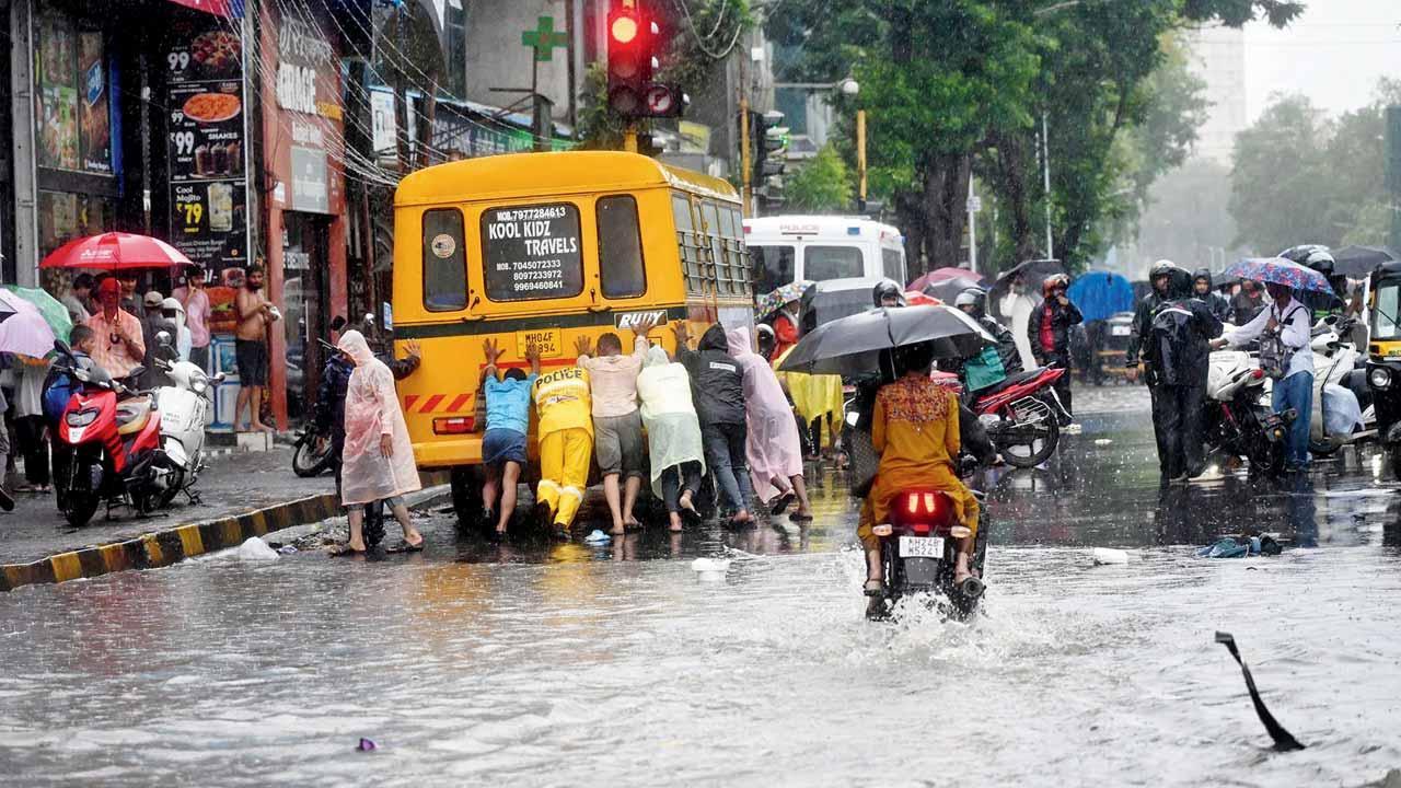 ભારે વરસાદને કારણે રસ્તા પર ભરાયેલા પાણીમાંથી પસાર થતી એક બસ બંધ પડી ગઈ હતી, જેને મુસાફરોએ ધક્કો મારવો પડ્યો હતો. તસવીર : અતુલ કાંબળે