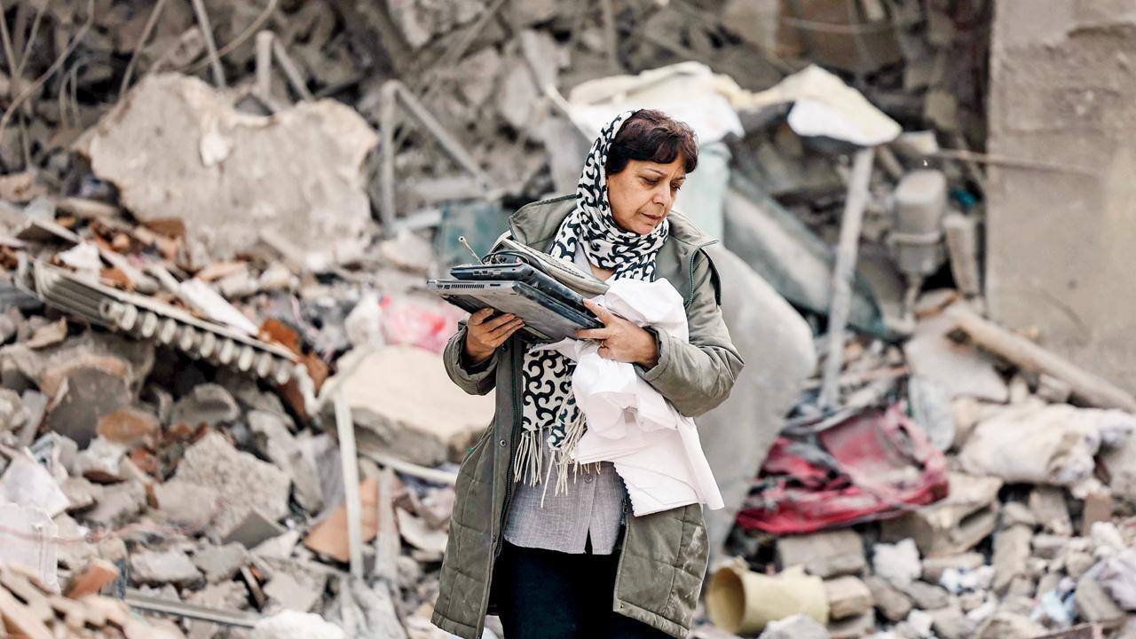 અમેરિકા-ઇઝરાયલના હુમલામાં તબાહ થઈ ગયેલા રહેણાક બિલ્ડિંગના કાટમાળમાંથી એક મહિલા પોતાની મહામૂલી ચીજો એકઠી કરી રહી છે.