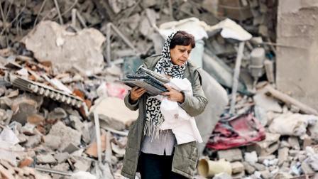 અમેરિકા-ઇઝરાયલના હુમલામાં તબાહ થઈ ગયેલા રહેણાક બિલ્ડિંગના કાટમાળમાંથી એક મહિલા પોતાની મહામૂલી ચીજો એકઠી કરી રહી છે.